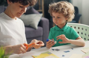 a woman and a child sitting at a table with scissors